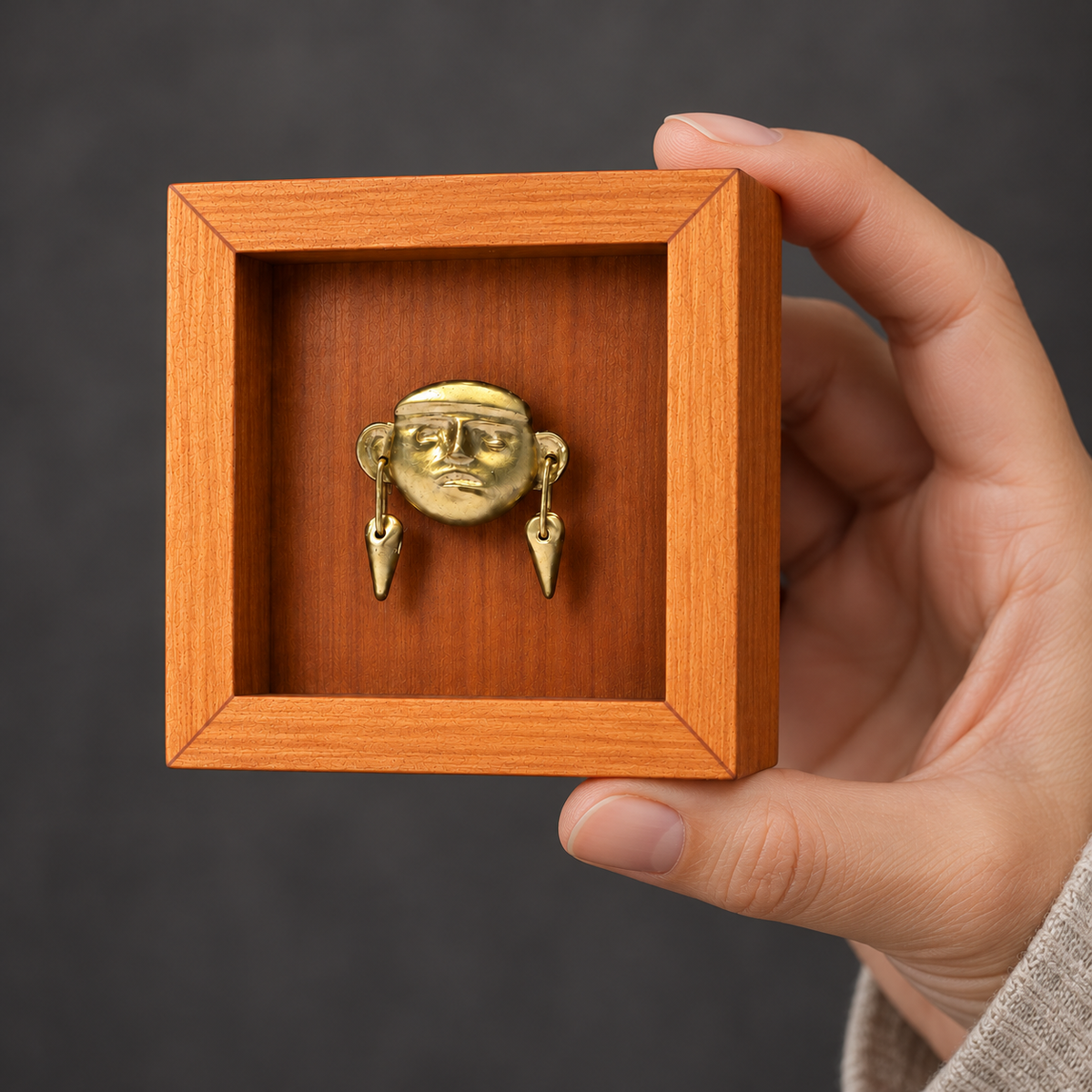Monito de Sipán · Mini Shadow Box 7 cm sostenido por el marco con una mano para apreciar su tamaño: recreación digital.